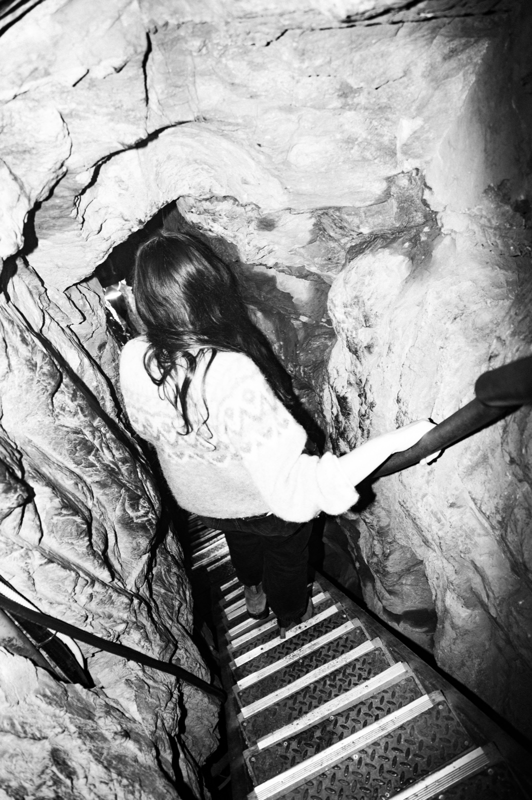 A guest descending the narrow crevice staircase, one hand on the rail